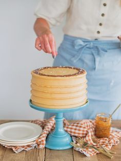 a woman is decorating a cake with icing