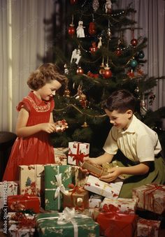 two children opening presents under the christmas tree