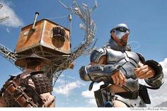 two men dressed in armor standing next to each other near a bird cage on a wire structure