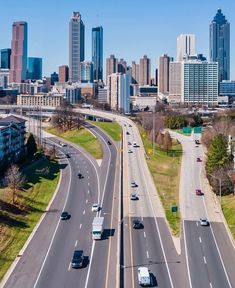 an aerial view of a highway with cars driving on it and the city skyline in the background