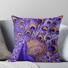 a purple and blue peacock throw pillow sitting on top of a couch