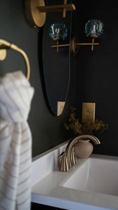 a white sink sitting under a mirror next to a gold faucet in a bathroom