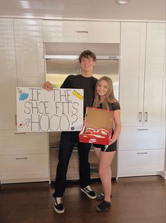 two people standing in a kitchen holding a sign that says see the sheep it shoots