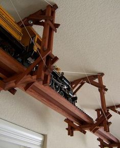 a toy train is sitting on top of a wooden shelf hanging from the ceiling above