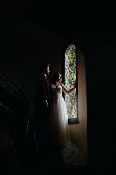 a bride and groom standing in front of a stained glass window