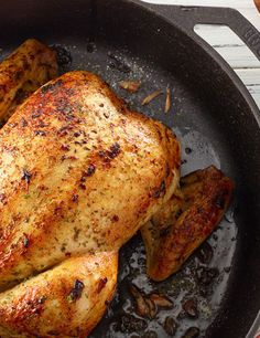 chicken cooking in a skillet with mushrooms and spices on the side for garnish