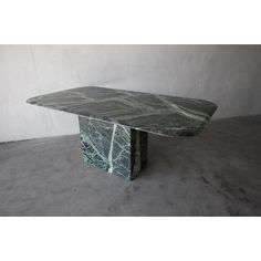 a green marble table sitting on top of a cement floor next to a white wall