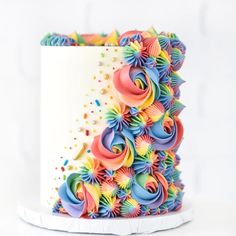 a multicolored cake with icing and sprinkles on the top