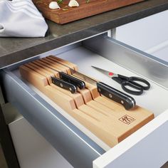 scissors and cutting board in drawer with knifes on counter next to utensils