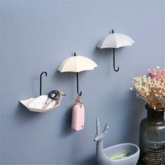 three umbrella hooks are hanging on the wall next to a vase with flowers and other items