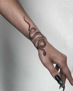 a person's hand with a tattoo on it and a snake on the wrist