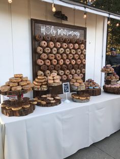 a table topped with lots of donuts on top of a white cloth covered table