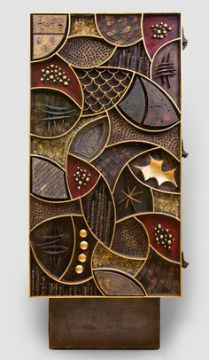 an art piece made out of metal and wood with different designs on the sides, including leaves