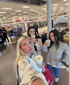 three women standing in a store holding drinks