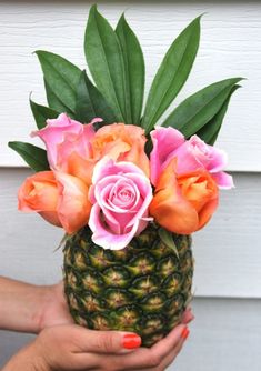 a person holding a pineapple with flowers in it