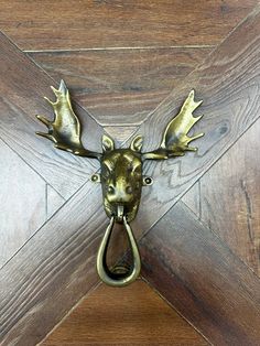 a metal deer head mounted to the side of a wooden door with a hook on it