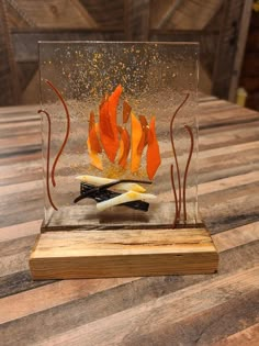 a glass sculpture with orange and yellow leaves in it on top of a wooden table