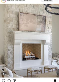 a living room with a fire place in the center and two white chairs around it