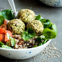 a white bowl filled with meatballs and veggies on top of a table