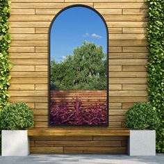 an arched window is shown in front of a wooden wall with plants and shrubs on it