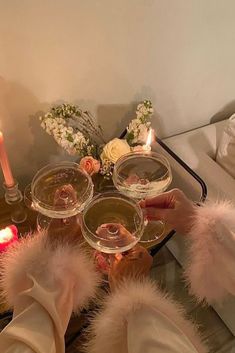 two people holding wine glasses in front of a table with candles and flowers on it