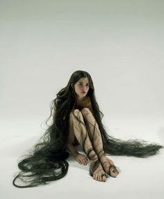 a woman with long hair sitting on the ground