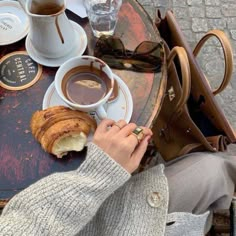 a person sitting at a table with coffee and croissants