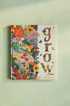 a book with flowers and letters on the cover is sitting on a green surface next to a wall