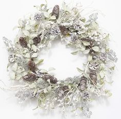 a white wreath with pine cones and greenery