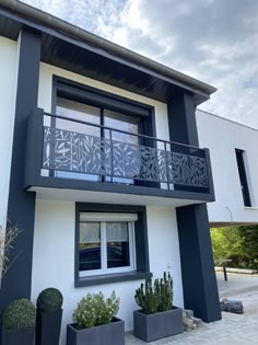 a white and black house with plants on the outside