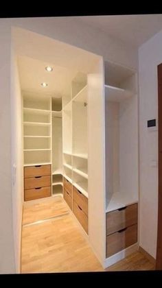 an empty walk in closet with white walls and wood floors, along with wooden drawers