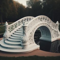 an ornate white bridge over a pond in a park