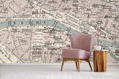 a pink chair sitting in front of a wall with a map on it's side