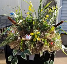 a basket filled with flowers and plants sitting on top of a wooden floor next to a building