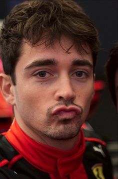 a close up of a person wearing a racing suit and looking at the camera with a serious look on his face