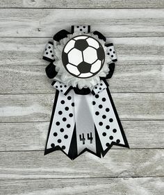 a black and white award ribbon with a soccer ball on it's center piece