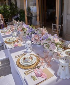 the table is set with pink and white flowers in vases, plates, and napkins