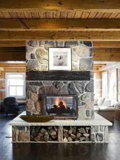 there is a fireplace in the middle of this living room with wood and stone walls