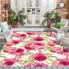 a rug with pink flowers on it in front of some chairs and potted plants