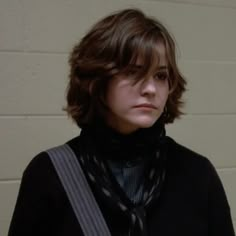 a young man wearing a black shirt and tie standing in front of a brick wall