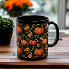 a black coffee mug sitting on top of a wooden table next to a potted plant