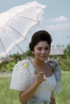 a woman in a white dress holding an umbrella