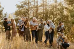 a group of people standing around each other in a field with trees and grass behind them