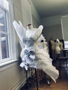 there is a mannequin made out of plastic bags on the stand in front of the window