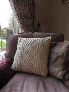 a couch with some pillows on top of it next to a glass door and window