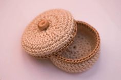 two crocheted baskets sitting next to each other on a white surface with a wooden button