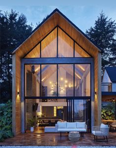 a modern house with large glass windows and wooden roof