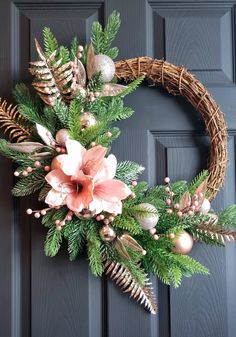 a wreath with pink flowers and greenery is hanging on the front door's black door