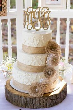 a three tiered wedding cake sitting on top of a wooden slice