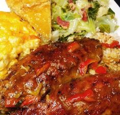 a white plate topped with meat, rice and veggies next to cornbreads